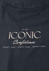 Námořnická modrá bavlněná trička s bílým textem: "IKONICKÉ Sebevědomí ZALOŽENO 2025" a dalšími frázemi o barvách. Hladký povrch.