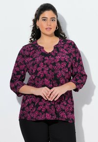 Czarna bluzka z różowym wzorem motyli, okrągły dekolt, rękawy o długości 3/4, detal w postaci guzika, lekka tkanina. Noszona z czarnym dołem.