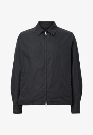 Chaqueta ligera negra con cuello, cierre frontal de cremallera y bolsillos laterales. Presenta un logotipo sutil en el lado izquierdo del pecho y una textura suave.
