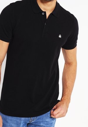 Czarna koszulka polo z bawełny, z klasycznym kołnierzykiem, krótkimi rękawami i małym białym logo na piersi. Prosty i dopasowany krój.