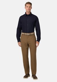 Námořnická košile na knoflíky, hnědé formální kalhoty, tkaný pásek, hnědé boty. Košile má dlouhé rukávy, kalhoty mají rovný střih.