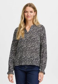 Schwarz-weiße Bluse mit V-Ausschnitt, langen Ärmeln mit umsäumten Säumen und einem abstrakten Muster. Aus weichem, leichtem Stoff.