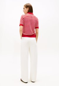 Punaste ja valgete triipudega lühikeste varrukatega polosärk, millele on lisatud valged laiade säärtega püksid. Sile tekstuur, soonikkoeline krae ja äär.