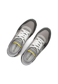 Szare trampki wykonane z siateczki i zamszu, z białymi sznurówkami, żółtymi akcentami oraz teksturowaną podeszwą, z logo po boku.