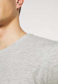 Grå kortermet T-skjorte med rund hals. Stoffet ser mykt og litt teksturert ut, med et subtilt heather-mønster.