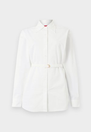 Λευκό πουκάμισο με μακριά μανίκια, κουμπιά, γιακά και λεπτή ζώνη στη μέση, παρουσιάζεται σε απλό φόντο.