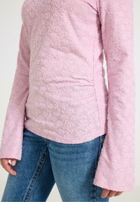 Roze bloementextuur top met lange uitlopende mouwen, voorzien van een gladde afwerking en een getailleerd ontwerp, gecombineerd met blauwe denim jeans.