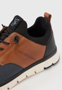 Barna bőr és fekete hálós sneaker, texturált felülettel, fehér talppal és a oldalán dombornyomott "SALAMANDER" logóval.