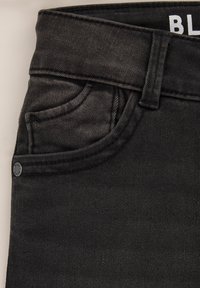 Čierne džínsy z denimu majú vysoký pás, dizajn s piatimi vreckami a kontrastným stehom. Zapínanie na gombík a zips s jemne textúrovanou tkaninou.