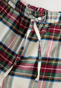 Cotton plaid shorts with an elastic waistband and drawstring. Features a red, green, and blue check pattern on a cream background.