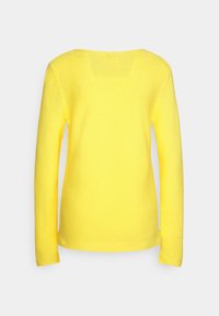 Haut jaune à manches longues avec un col rond, une texture côtelée et un ourlet droit. Le dos est lisse, sans décorations supplémentaires.