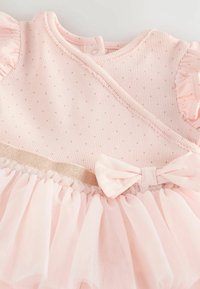 Světle růžové dětské šaty s malými tečkami, nařasenými krátkými rukávy, páskem se mašlí a nařasenou tylovou sukní.