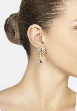 Silver earrings featuring a blue gemstone in a textured floral design, with a teardrop accent hanging beneath.