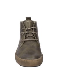 Bottines en cuir marron avec bout rond, couture décorative et fermeture à lacets. Semelle en caoutchouc épaisse et texture douce.
