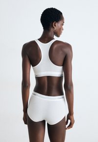 Weißer Baumwoll-Sport-BH und Unterhose mit Logo-Bund, ausgestattet mit Racerback-Design und glattem, enganliegendem Stoff.