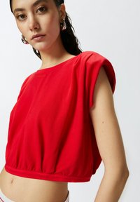 Top corto rosso con maniche corte e svasate, tessuto texturizzato e orlo arricciato. Presenta il logo "PINCO" in oro sul fronte.