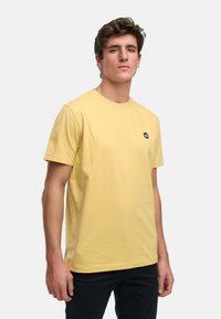 Lichtgele T-shirt met korte mouwen van katoen, met een ronde hals en een klein donker logo op de linkerborst.