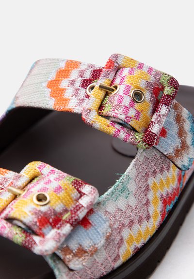 Lanières de sandales en tissu tissé coloré avec deux boucles à motifs réglables sur une semelle noire, sur fond blanc.