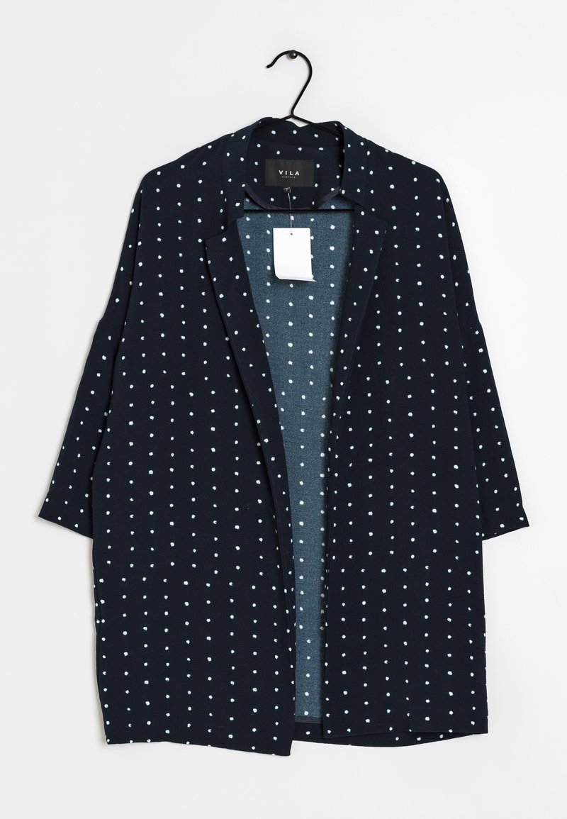 Marineblauwe cardigan met open voorkant, witte polka dots, driekwartmouwen en een gladde textuur. Etiket bevestigd aan de binnenkant van de kraag.