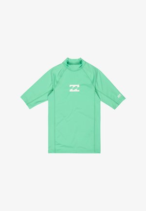 Zielono-miętowa koszulka rash guard z krótkim rękawem, wysokim kołnierzem, białym logo fali na środku klatki piersiowej i małym napisem na prawym rękawie.