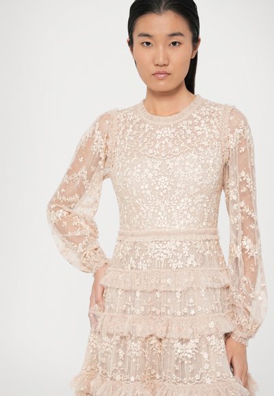 Šviesiai rožinė, sluoksniuota suknelė, pagaminta iš permatomos medžiagos su gėlių siuvinėjimais ir volanėlėmis; ilgomis rankovėmis ir apvaliu iškirpimu.