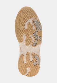 Semelle de chaussure présentant un design ondulé avec du caoutchouc beige, des motifs texturés et des nuances variées de gris, marron et crème partout.