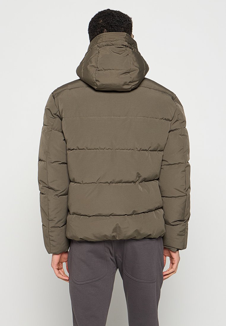 Olivgrüne Daunenjacke mit Kapuze, die eine gesteppten Textur, horizontale Nähte und eine entspannte Passform aufweist. Die Rückansicht zeigt ein einfaches Design.