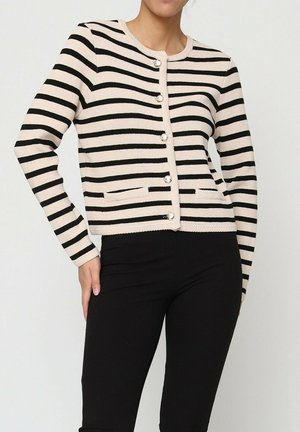 Gilet rayé en tricot crème et noir, avec un col rond, des boutons ressemblant à des perles et deux poches avant. Manches longues, design ajusté.