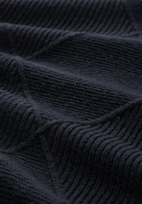 Ciemny dzianinowy materiał z teksturowanym, prążkowanym wzorem w diagonalne linie, prezentujący grubą włóczkę w głębokim granatowym kolorze.