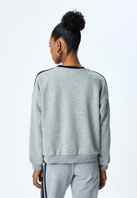 Grijze katoen sweatshirt met een losse fit, geribde manchetten en een ronde halslijn, met marineblauwe accenten langs de schouders en achterkant.