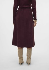 Bordo midi-hame, jossa on kootut vyötärönauha ja joka on valmistettu teksturoituneesta kankaasta. Yhdistetty beigeihin polvimittaisiin saappaisiin. Yksinkertainen ja virtaava muotoilu.