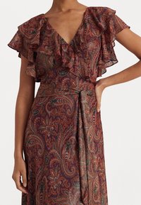 Gerafftes, kurzärmeliges Kleid im Paisleymuster mit tiefem V-Ausschnitt. Reichhaltiger burgunderroter und grüner Stoff mit subtiler Glanz und Taillenband.