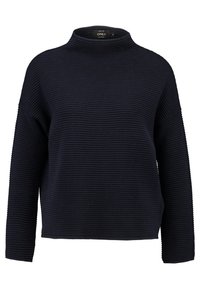 Granatowy sweter z golfem o prążkowanej fakturze, szerokimi rękawami i luźnym krojem. Dół swetra jest prosty i sięga do talii.