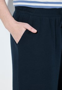 Marine joggers van gestructureerde stof met een elastische tailleband en zijzakken. Gedetailleerd met een subtiel patroon voor extra uitstraling.