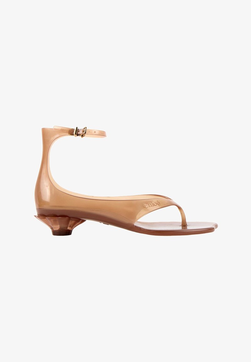 Sandale beige brillante avec talon sculpté bas, bride de cheville avec boucle, design à lanière d'orteil et nom de marque embossé sur le côté.