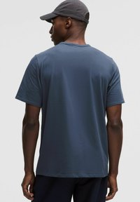 T-shirt en coton bleu marine avec un col rond et des manches courtes. La vue arrière met en avant une texture lisse et une coupe décontractée.