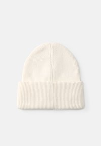 Beanie lavorato a maglia di colore crema con texture a coste e risvolto, caratterizzato da una parte superiore senza cuciture. Tessuto morbido e caldo per il comfort.