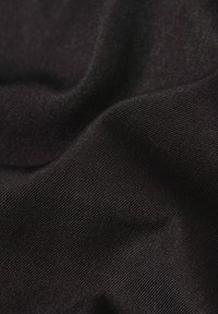 Svart tyg med en slät, lätt glänsande textur. Ytan visar fin, horisontell ribbning, vilket indikerar ett stickat eller elastiskt material.