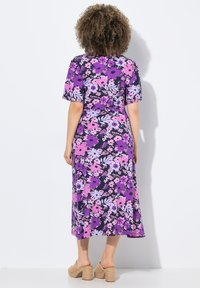 Fialové květinové midi šaty s krátkými rukávy, zdobené kombinací růžových a levandulových květin na černém pozadí. Doplněné béžovými blokovými podpatky.