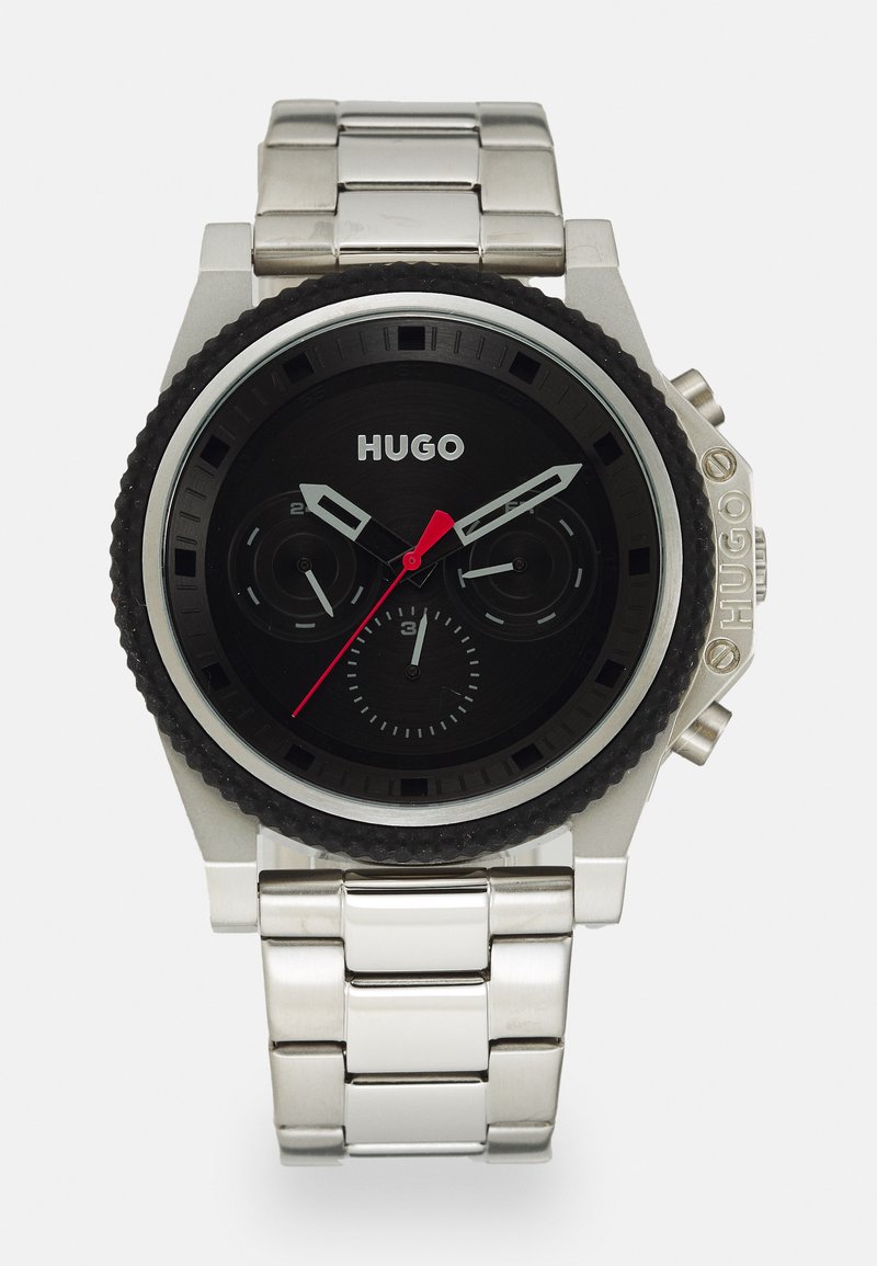 Silver metallarmband med svart urtavla, som har två kronografsubdials, silverfärgade timmarkeringar, och en röd sekundvisare. Gummidetalj på bezeln.