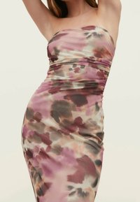 Robe bustier en tissu léger et fluide. Présente un motif abstrait rose, marron et crème avec un détail froncé à la taille.