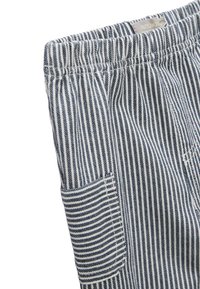 Pantalons en coton rayés présentant des rayures verticales bleu marine et blanches, une taille élastique et une poche latérale avec un motif de rayures assorti.