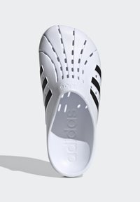 Infradito bianchi con accenti a strisce nere. Realizzati in un materiale liscio con fori di ventilazione e branding impresso sulla soletta.