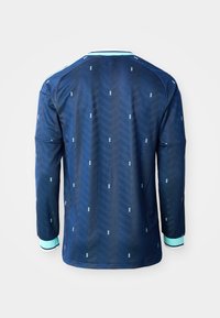 Maillot de sport à manches longues bleu marine avec un motif chevron subtil et de petits accents bleu clair, poignets bleu clair avec bordure noire et blanche.