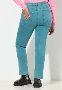 Jasnoniebieskie jeansy z denimu o średnim stanie, prostych nogawkach i dwoma tylnymi kieszeniami. W zestawie z czarnymi butami na platformie.