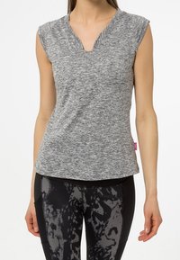 Top atlético gris de manga corta con cuello en V y tejido texturizado, combinado con leggings negros que presentan un sutil patrón abstracto.