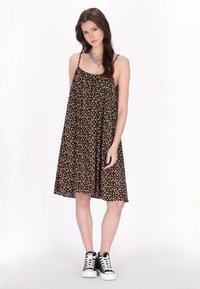 Rochie neagră fără mâneci, cu un imprimeu floral mic, formă fluidă și bretele ajustabile, asortată cu adidași negri cu glezna înaltă.