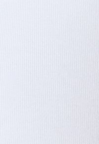 Wit ribstof met een fijne textuur. Het oppervlak is glad en toont verticale lijnen die zijn ontstaan door het ribbelpatroon.