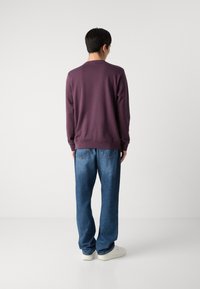 Lilla hettegenser med ribbet kant, parret med løse blå jeans. Outfiten har et enkelt design og en avslappet silhuett.