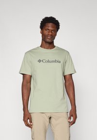 Light green cotton t-shirt featuring a dark grey "Columbia" logo, round neck, and short sleeves. Smooth texture, casual fit.